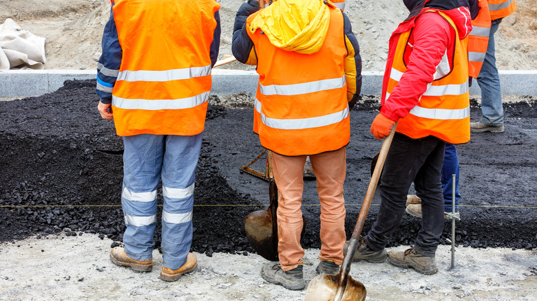 Workers in orange vests laying asphalt