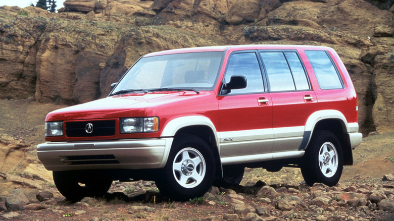 A two-tone 1996 Acura SLX SUV parked on rocks and dirt