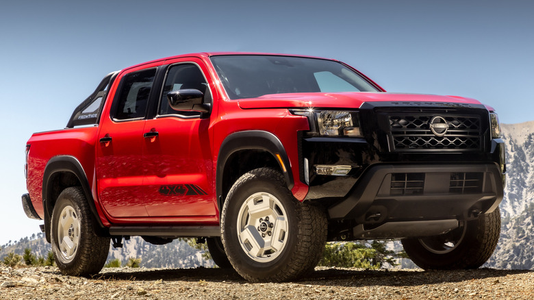 A front 3/4 shot of a red 2024 Nissan Frontier Hardbody Edition with mountains in the background
