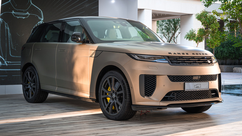 A rose gold Range Rover Sport parked in front of a modern home.