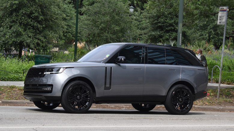 A matte gray Range Rover Vogue parked in front of a line of trees.