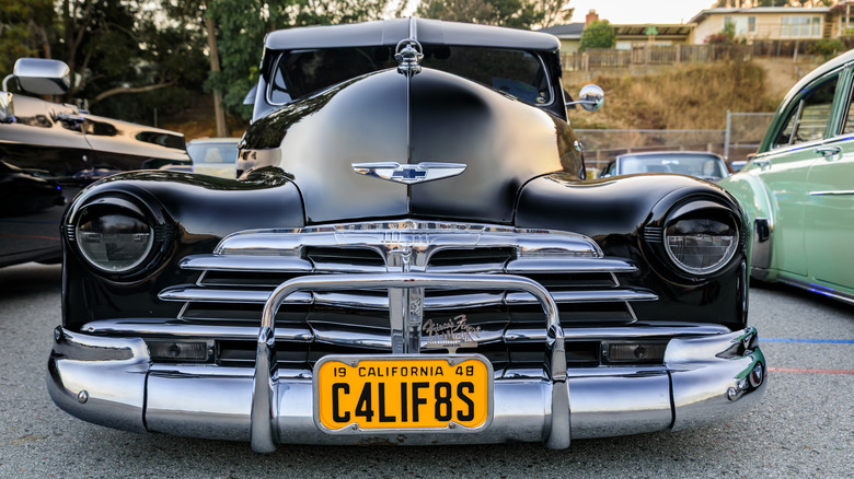 A black 1948 Chevrolet Fleetline classic car at a car show with bold chrome grille bars and large sealed beam headlights.