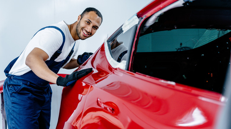 A man admiring a freshly painted red car