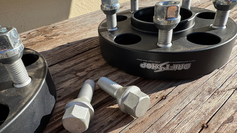 A pair of wheel spacers shown with lug nuts and lug bolts