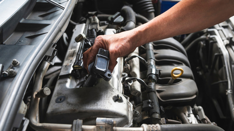 A mechanic inspecting the coil pack of an engine