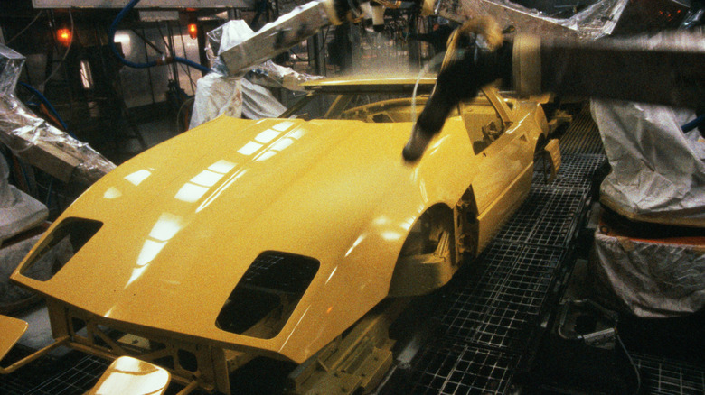 A yellow C4 Chevrolet Corvette getting painted on the assembly line