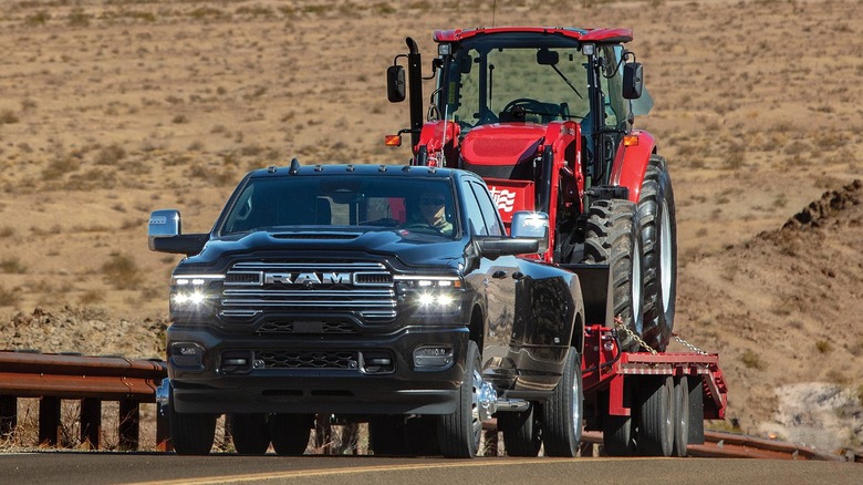 2025 Ram Heavy Duty towing a large tractor up a hill