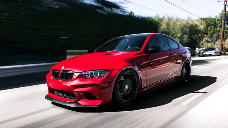 red 2009 BMW M3 E92 on the road with trees in the background