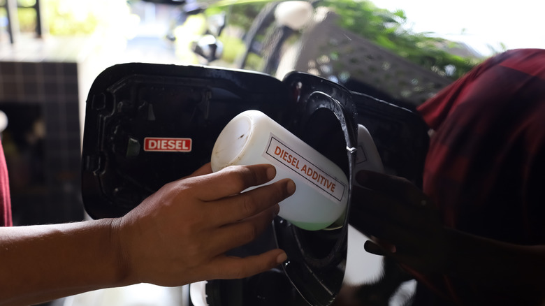 A person pouring diesel additives into the fuel tank