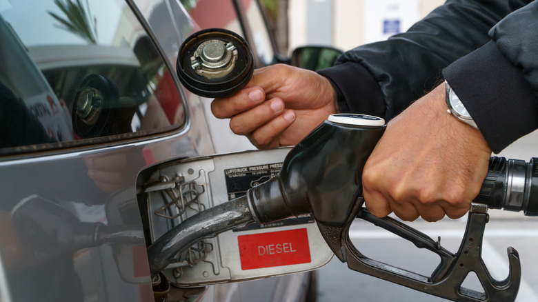The hands of a man filling up a car with gasoline at a gas station