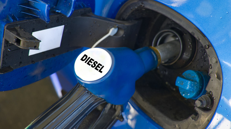 A close-up of a fuel-filling nozzle labeled 'Diesel' at a gas station