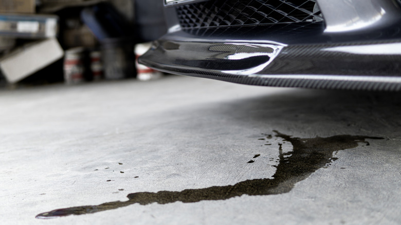 An oil leak stain on a driveway beneath a parked car