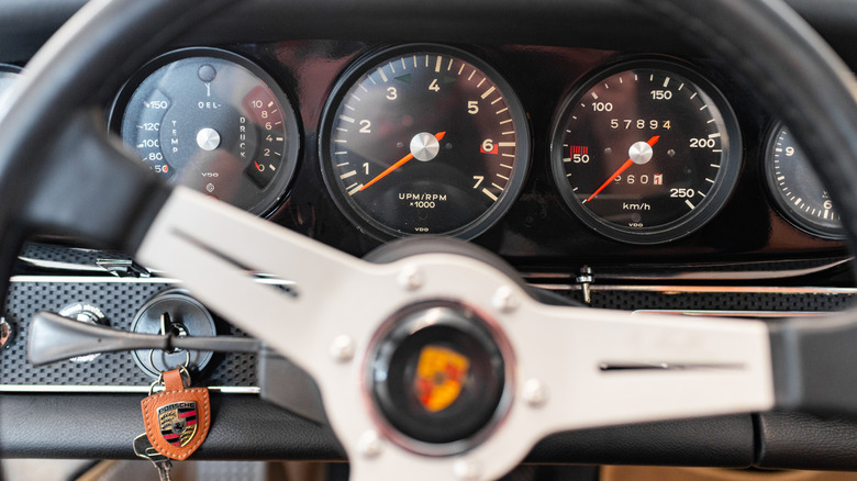 The steering wheel and gauge cluster of a 1969 Porsche 911T showing the ignition key on the left side