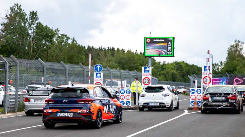 Ordinary cars waiting at the track barrier for entrance to the Nürburgring.