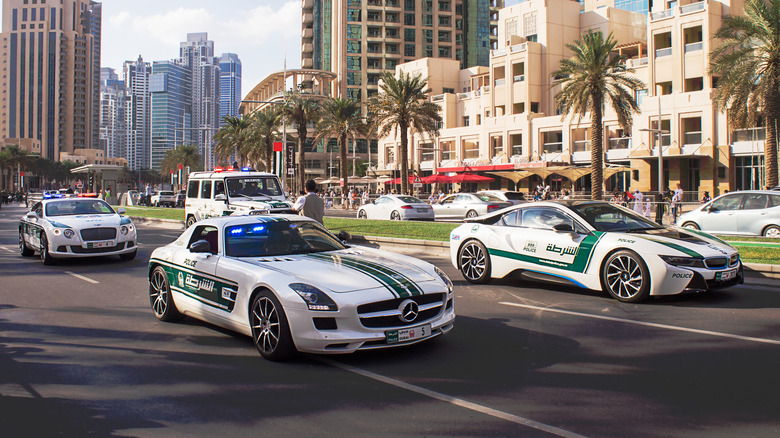 Dubai Police cars, including a BMW i8 and Mercedes SLS, driving on the road