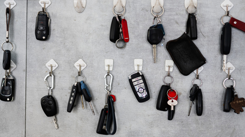 A collection of different types of car keys and key fobs, hanging in in a valet cabinet.