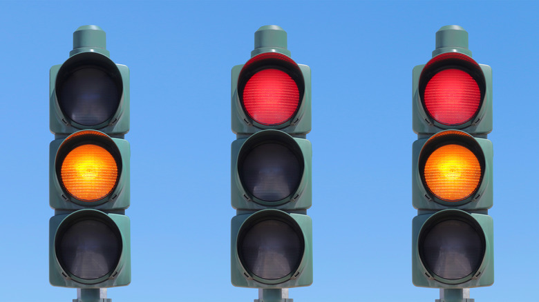 A set of three traffic lights with yellow, red, and red plus yellow lights active