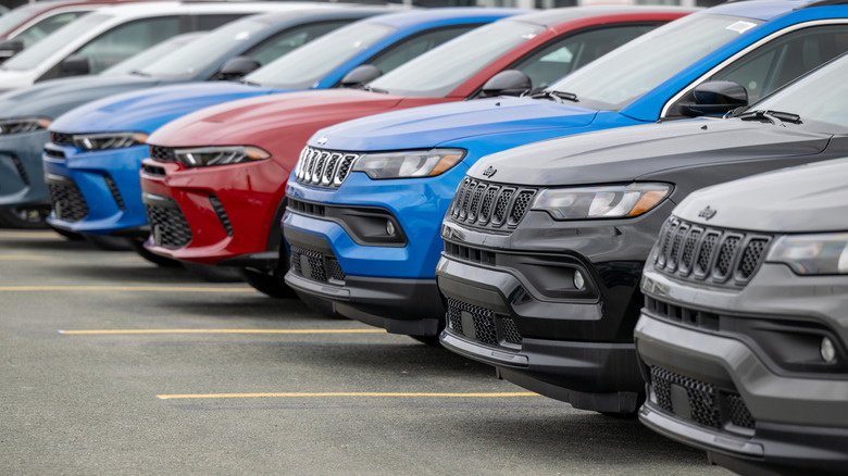 A lineup of fleet vehicles from Jeep and Dodge, parked in a row on a dealer lot