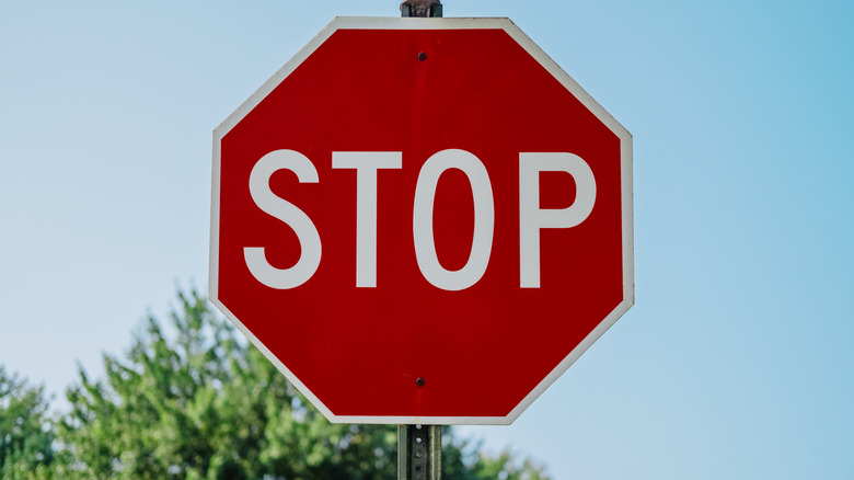 A red stop sign with a tree behind it