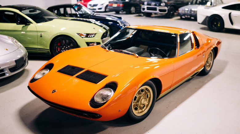 An orange Lamborghini Miura standing in front of other sports cars