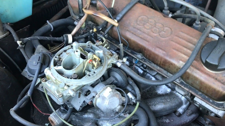 A five-cylinder Audi 100 C2 5S engine with dirty valve cover and air cleaner removed from the carburetor.