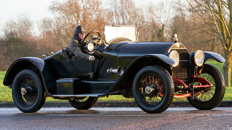 A black Stutz Bear Cat roadster parked with grass and trees behind it.