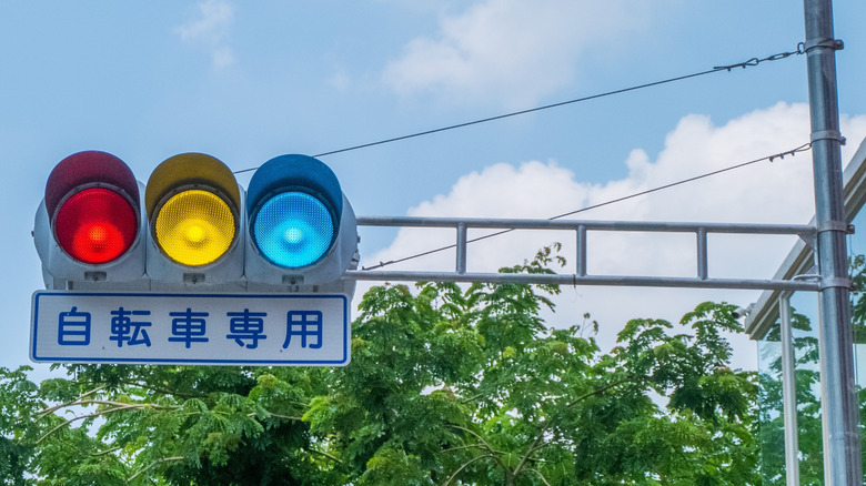 A blue-green traffic light attached to a pole in Japan