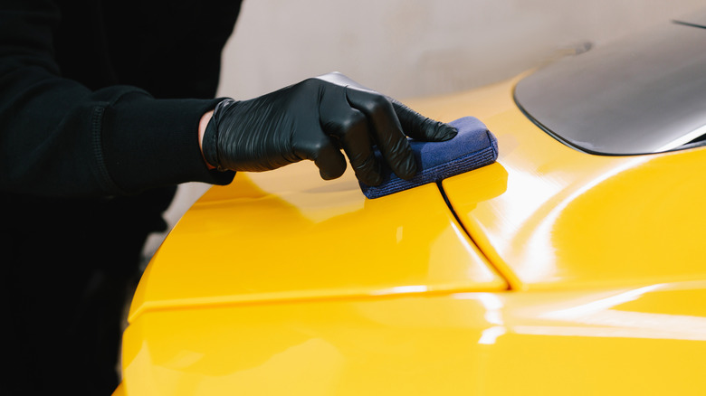 A detailer applying a ceramic coating over yellow car paint