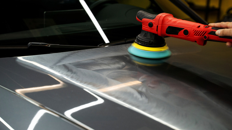 A detailer using a DA polisher on a car's hood