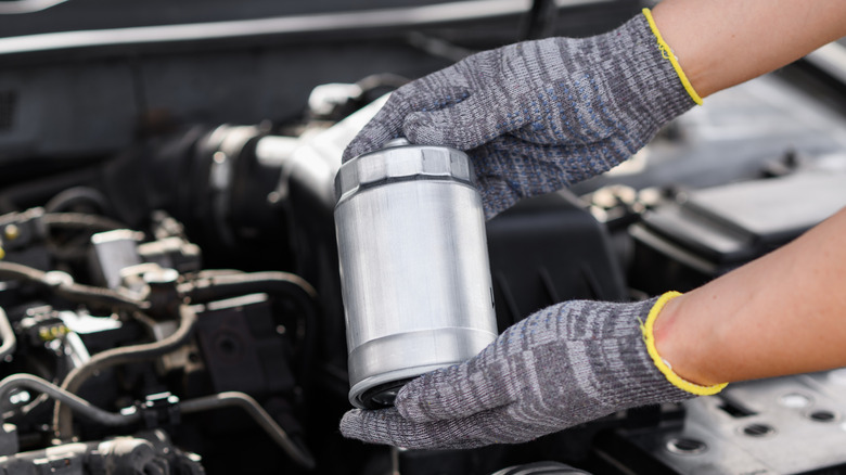 A mechanic holding a new fuel filter for a diesel car