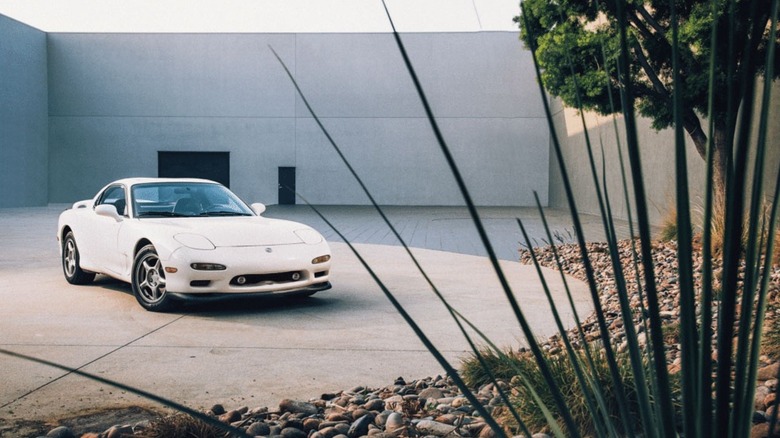 A white FD-series Mazda RX-7 parked outside a building