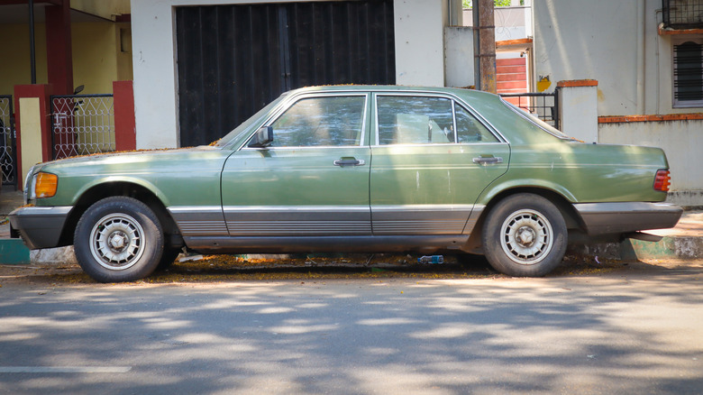 A green Mercedes W126 parked on the street.