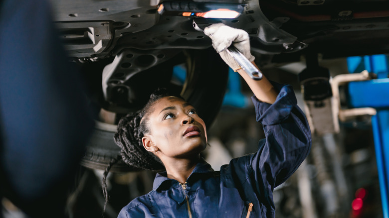 Black woman mechanic working on a car