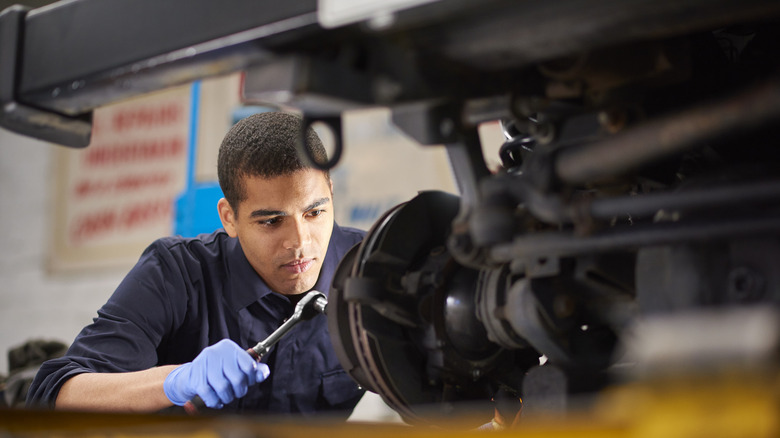 Black mechanic working on brake pads