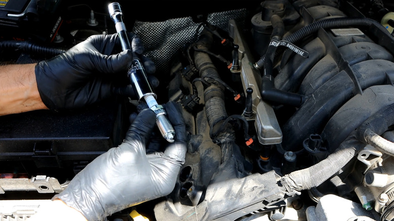 A man changing a spark plug on a Hemi engine in a Jeep.