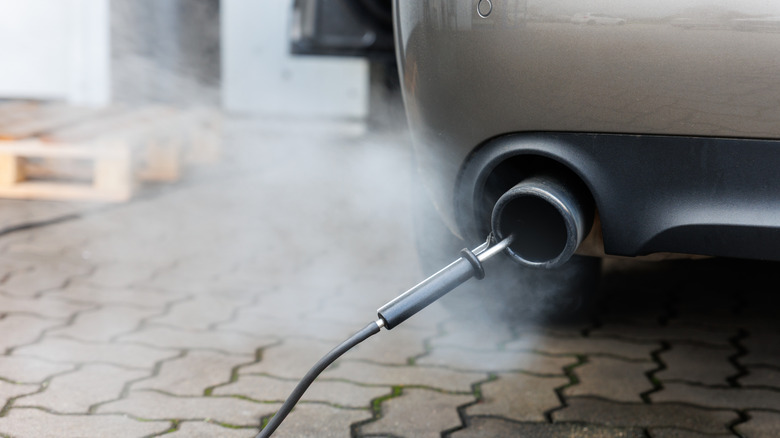 A close-up of a vehicle exhaust pipe with an emissions testing probe inserted