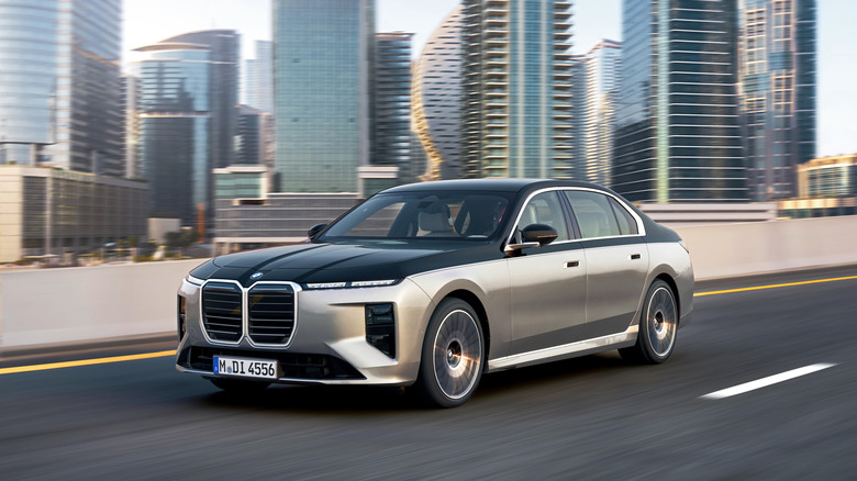 A silver and black BMW 740 xDrive driving down the highway with city buildings in the background