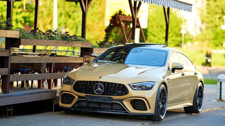 A yellow 2024 Mercedes-AMG CLA45 S Coupe parked in front of outdoor cafe