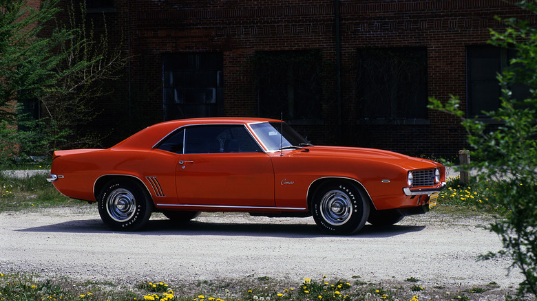 A Red 1969 Camaro pictured in front of an old brick building.