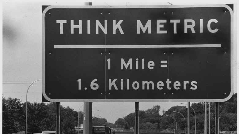 A traffic sign near the US border in Quebec reads "THINK METRIC, 1 Mile = 1.6 Kilometers." The reminds travelers from the United States that metric measurements are used in Canada.