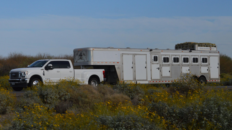 A white Ford F-450 towing a massive trailer with a Gooseneck hitch.