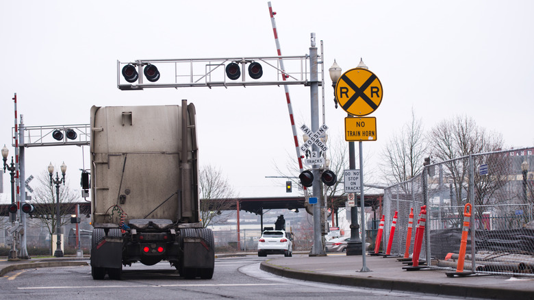 An advance warning railroad crossing sign with a 'no train horn' sign signals ahead of a crossbuck and barriers