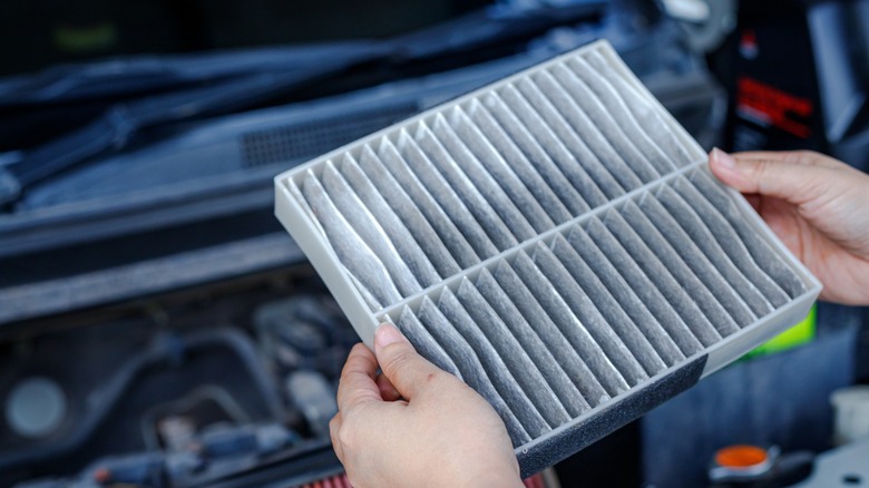 Dirty air filter removed from a car engine bay