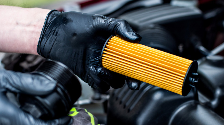 Mechanic holding a new oil filter for a car's engine