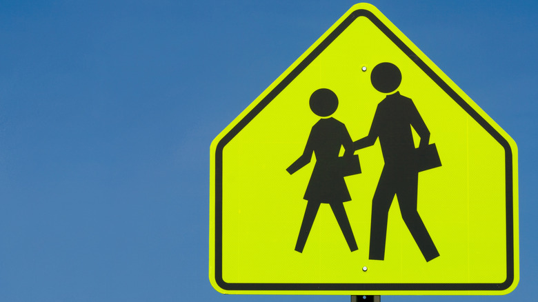A fluorescent sign warns drivers of a school zone to protect children and caretakers