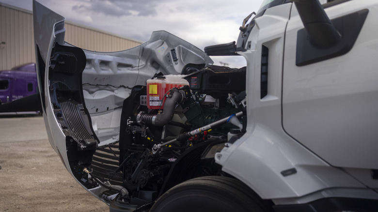 A semi truck with its hood folded open revealing the diesel engine