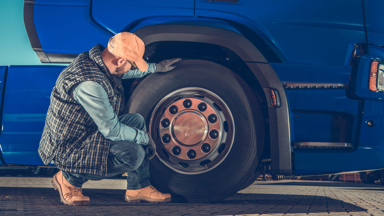 A driver checking the steer tires of a semi truck