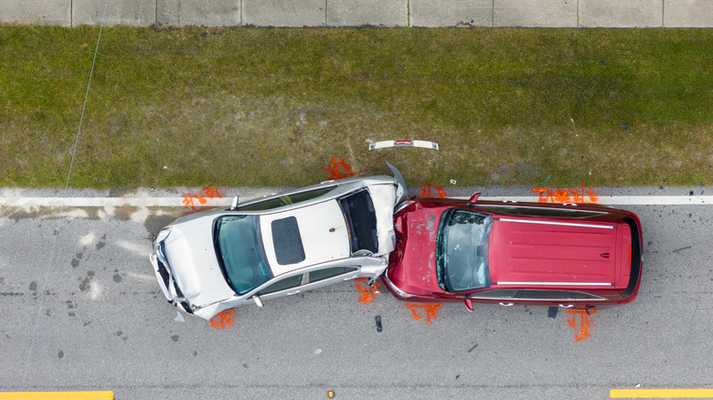 An overhead shot of a red minivan rear-ending a silver sedan on the shoulder of the highway
