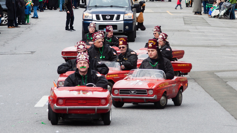 Shriners driving in miniature Ford Mustangs at an event.