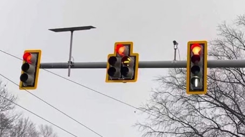A set of red light traffic lights with a white vertical light also lit.